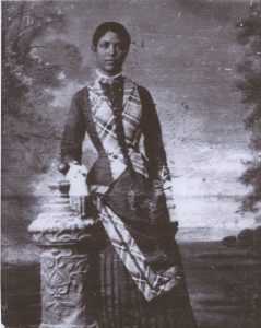 Annie Box Neal Standing in a dark and plaid dress