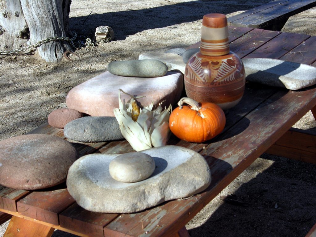 Heritage Garden manos and metates, mixed maize ears, miniature pumpkin, Mexican pottery water jar