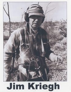 Black and white photo of Jim Kriegh wearing a hat and flannel shirt while searching for meterorites.