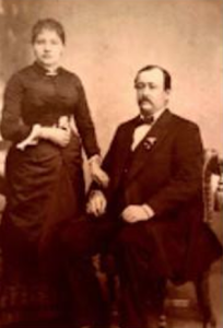 Sophie and Johann Zellweger. She is standing while John is seated in a chair.