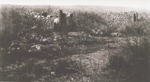 Romero Ruin, circa 1910 - man standing by rock walls of builiding
